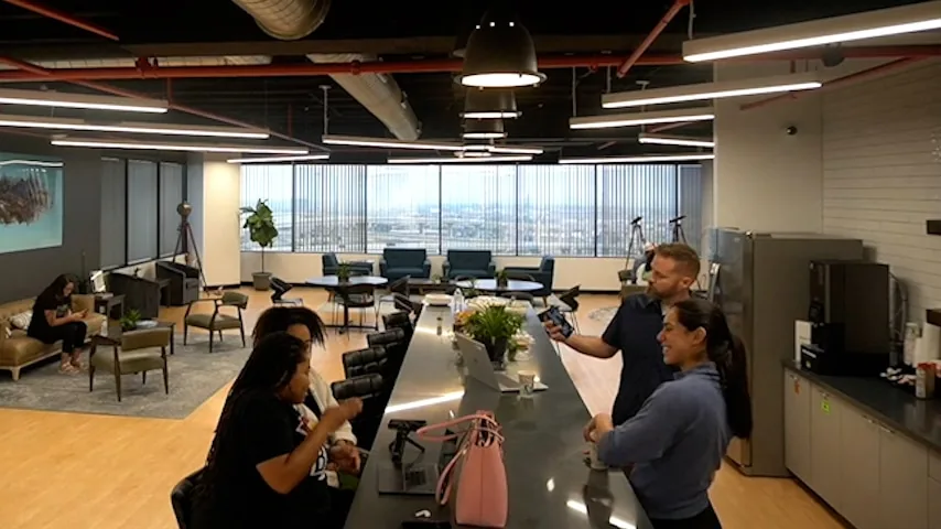 Members working and talking at the community bar in the open coworking area at SA Cowork in San Antonio
